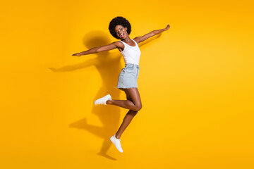 Full length body size view of pretty slim cheerful wavy-haired girl jumping having fun isolated over bright yellow color background