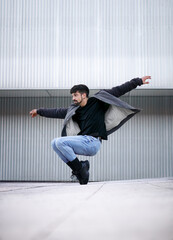 young caucasian man with beard in black t-shirt jacket jeans and boots, dancing contemporary and...