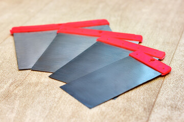 The perspective view a set of the stainless steel flexible-blades spatulas lying on the wooden...