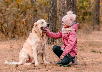 Little girl with golden retriever in forest