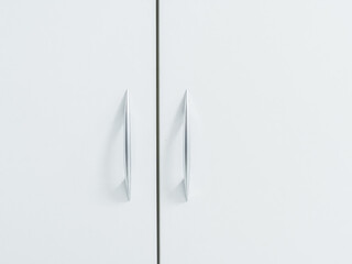White cabinet doors with thin metal handles. Minimalistic light cupboard. Close-up