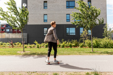 people and leisure concept - young man or teenage boy riding skateboard on city street