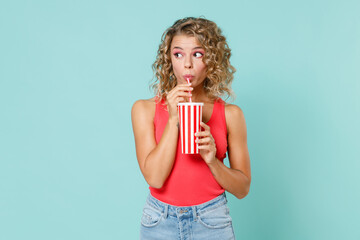 Shocked amazed pretty young blonde woman 20s wearing pink basic casual tank top standing hold cup...