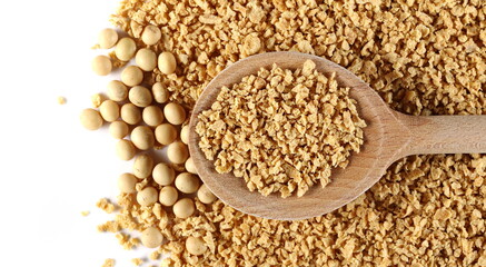 Raw soybeans with soy flakes pile in wooden spoon isolated on white background, top view