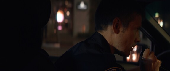 CU Police officer talking on CB radio while driving police vehicle through city streets at night