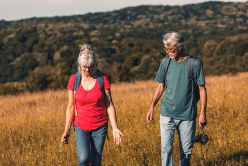 Active senior couple hiking in nature with backpacks, enjoying their adventure in nature.