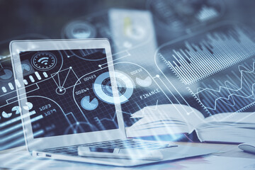 Computer on desktop in office with technology theme hologram. Double exposure. Tech concept.