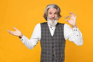 Confused elderly gray-haired business man in checkered suit waistcoat shirt hold bitcoin coin currency spreading hands isolated on yellow background studio portrait. Achievement career wealth concept.
