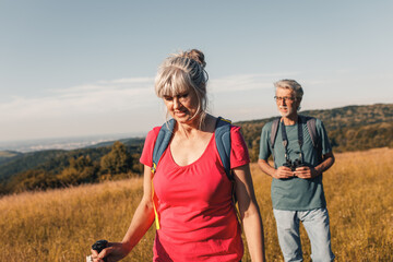 Active senior couple hiking in nature with backpacks, enjoying their adventure in nature.