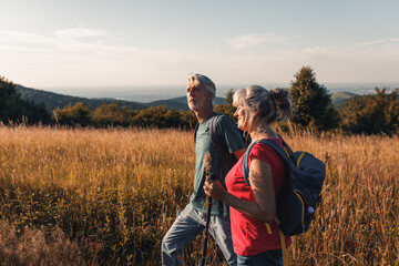 Active senior couple hiking in nature with backpacks, enjoying their adventure in nature.