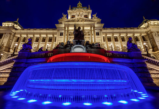 A czech National Museum in Prague in night with illuminated front fasade and colourful fountain.