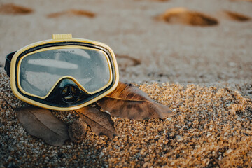 Diving Goggles lying on the sandy beach. snorkel on sandy background. Travel and Summer vacation swimming concept.
