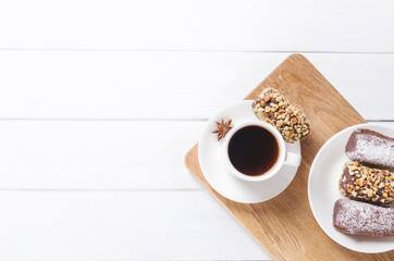 Black coffee cup with anise, cinnamnon and chocolate sweets on wooden background. Flat lay, copy space