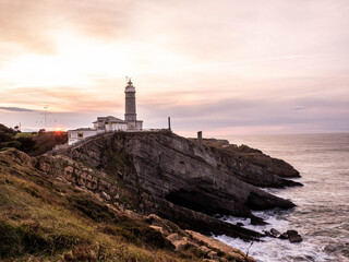 Fototapeta na wymiar An amazing sunset with a lighthouse landscape in the north coast of Spain