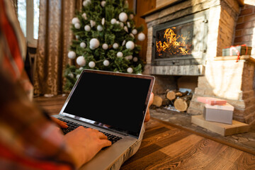 Naklejka na ściany i meble Happy woman looking in laptop in front of Christmas tree