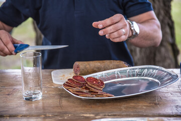 Cutting homemade sausage with a sharp knife on thin pieces for appetizer