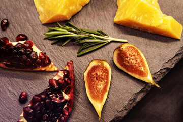 Fruits and slices of hard cheese on a background of dark stone countertops. Still life of healthy products. Close-up