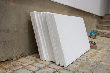 white styrofoam near the house,styrofoam sheets stacked to the wall for repair and insulation of the facade of the house