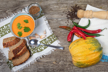 Pumpkin soup with brad onions and red pepper on the wooden table, top view