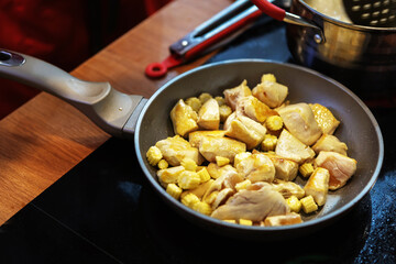 Chicken breast and corn are fried in a pan. Cooking vegetables and meat in a pan