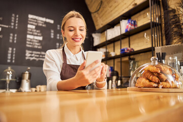 Happy smiling woman in uniform looking at the screen cell phone