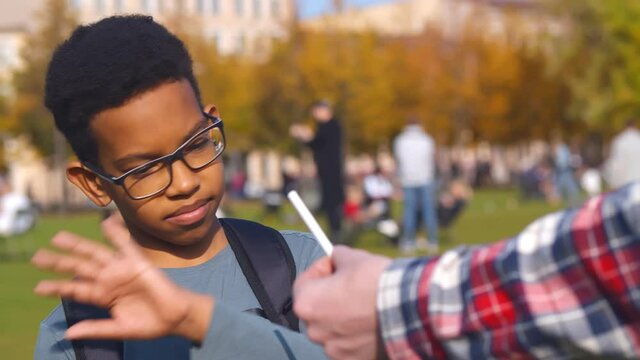 African preteen boy refusing cigarette offered by dealer outdoors