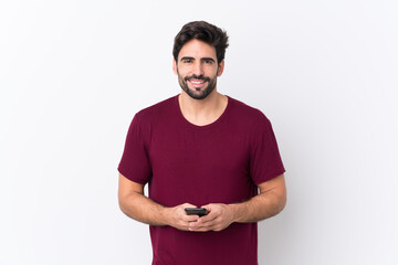 Fototapeta premium Young handsome man with beard over isolated white background sending a message with the mobile