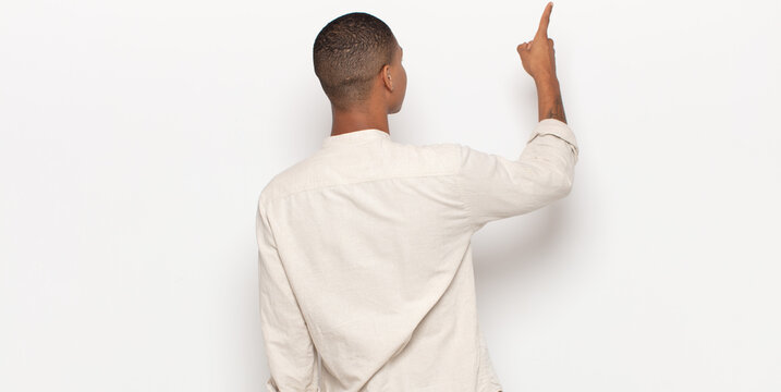 Young Black Man Standing And Pointing To Object On Copy Space, Rear View