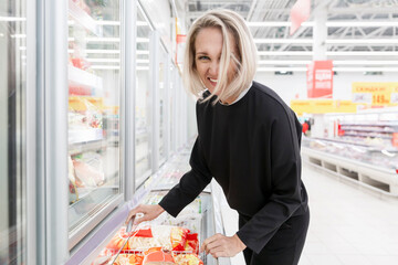 Laughing young woman in the frozen food department in a large light supermarket.