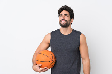 Basketball player man with beard over isolated white background looking up while smiling