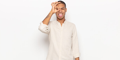 young black man smiling happily with funny face, joking and looking through peephole, spying on...