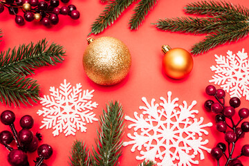 top view of spruce, baubles, snowflakes and berries on red background