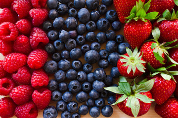 Fresh Strawberry, blueberry and raspberry.Colorful fresh forest fruits on wooden board background.