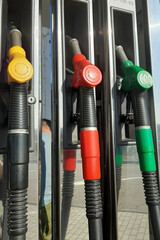 Multicolored fuel pistols on fuel station.