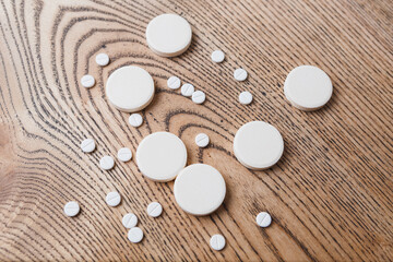 Fototapeta na wymiar white small and large round pills on a wooden background close-up. Pharmaceutical drugs for the treatment of diseases on a wooden table
