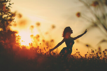 Silhouette of a slender poetic girl in a field at sunset among the tsevts - obrazy, fototapety, plakaty