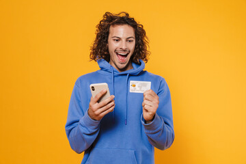 Excited caucasian guy posing cellphone and credit card