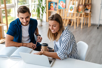 Young caucasian man and woman studying with laptop in classroom