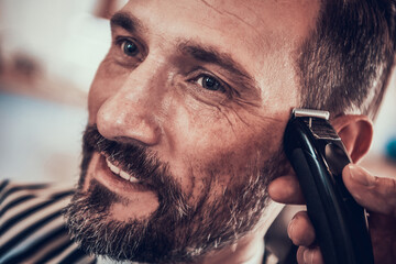 Man sits in barbershop while he gets new haircut. 