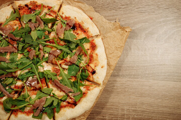 fresh pizza with herbs, tuna and balsamic sauce on food paper on a wooden table in a cozy cafe