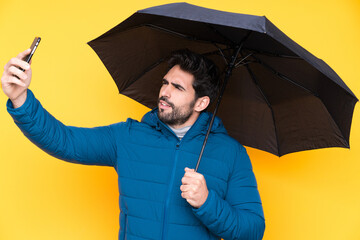 Man holding an umbrella over isolated yellow background