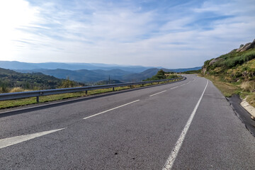 Asphalt road, with shoulder, crossing the mountains of the northern region of Portugal on a sunny day