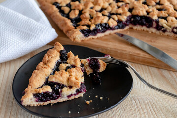 a plate with berry pie, blueberry pie on the background of the pie, next to there is a cup of tea