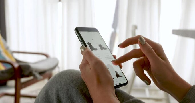 Woman browsing smartphone screen ordering clothes at home online