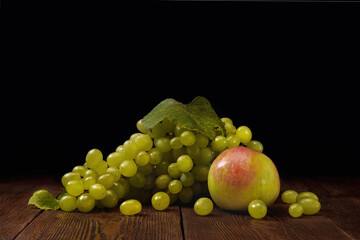 Ripe green grape and sweet apple on wooden table over dark background.