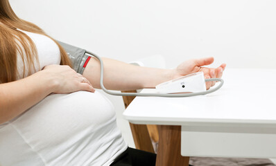 Obraz na płótnie Canvas The pregnant woman measures blood pressure at home