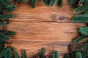 Flat lay with pine branches and anise stars on brown wooden background, new year concept