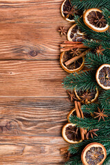 Top view of dry orange slices, anise stars, cinnamon sticks and pine branches on brown wooden background
