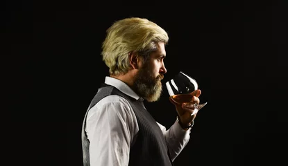 Fotobehang Elegant macho drink cognac. Matured in sherry casks. Whisky tasting. Sommelier tastes expensive drink. Good indication of condition of whisky. Bearded businessman in elegant suit with glass of whisky © be free