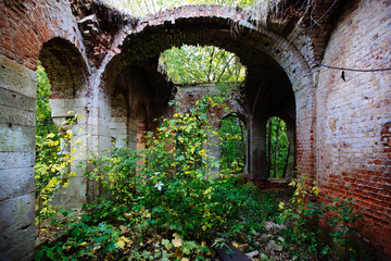 Fototapeta na wymiar Old ancient abandoned red brick ruins overgrown by plants